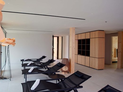 Wellness holiday in Bavaria with mountain view Relaxation room with lounge chairs, towels, and modern wooden interior design
