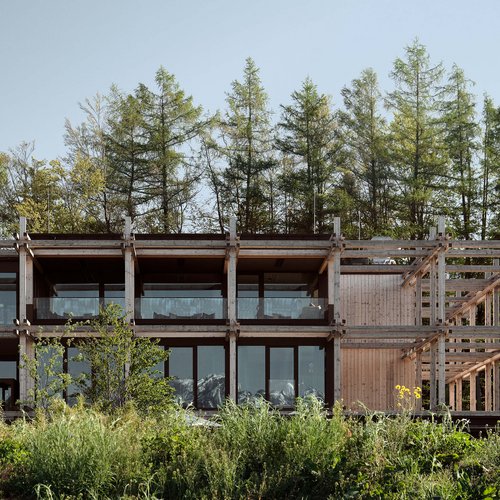 Hotel BERGEBLICK für Wellness in Bad Tölz Modernes Holzhaus vor Wald mit großen Fenstern und Garten