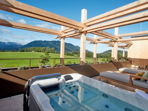 Your romantic hotel in Germany with mountain views Outdoor hot tub and lounge chairs overlooking green fields and mountains