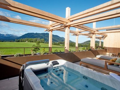 Your romantic hotel in Germany with mountain views Outdoor hot tub and lounge chairs overlooking green fields and mountains