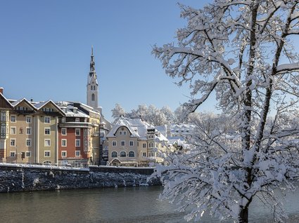 Sehenswert: Bad Tölz Winterliche Stadt mit Schnee bedeckten Häusern und Bäumen am Fluss