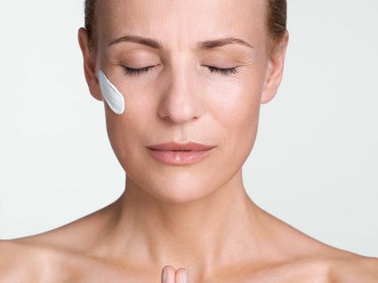 Bad Tölz: wellness & beauty Woman with closed eyes, face cream on cheek, praying with hands together