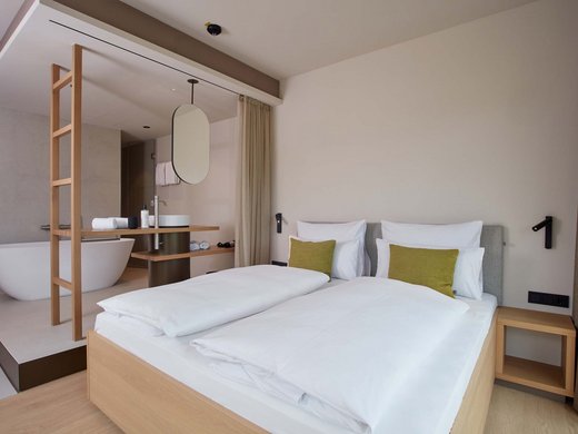 Hotel mit Badewanne im Zimmer in Bayern: BERGEBLICK Modernes Hotelzimmer mit Doppelbett und offenen Badezimmer mit Badewanne
