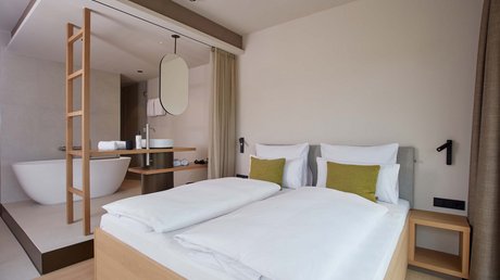 Pictures of a dream holiday in Bad Tölz Modern hotel room with double bed and open bathroom featuring a bathtub