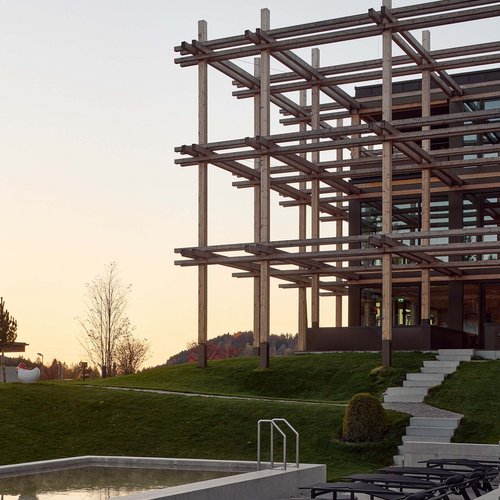 Hotel BERGEBLICK für Wellness in Bad Tölz Moderne Terrasse mit Liegestühlen, Pool und Holzrahmenbau bei Sonnenuntergang