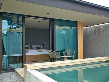 Hotel mit Whirlpool im Zimmer in Bayern Moderner Raum mit Doppelbett, Stühlen und Pool vor großer Glasscheibe