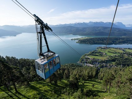 BERGEBLICK: dein Wanderhotel in Bayern Blaue Seilbahn über grünem Wald mit Blick auf See und Berge