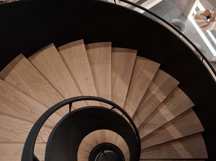 A holiday amidst nature in Germany Spiral wooden staircase with black railing in modern interior space