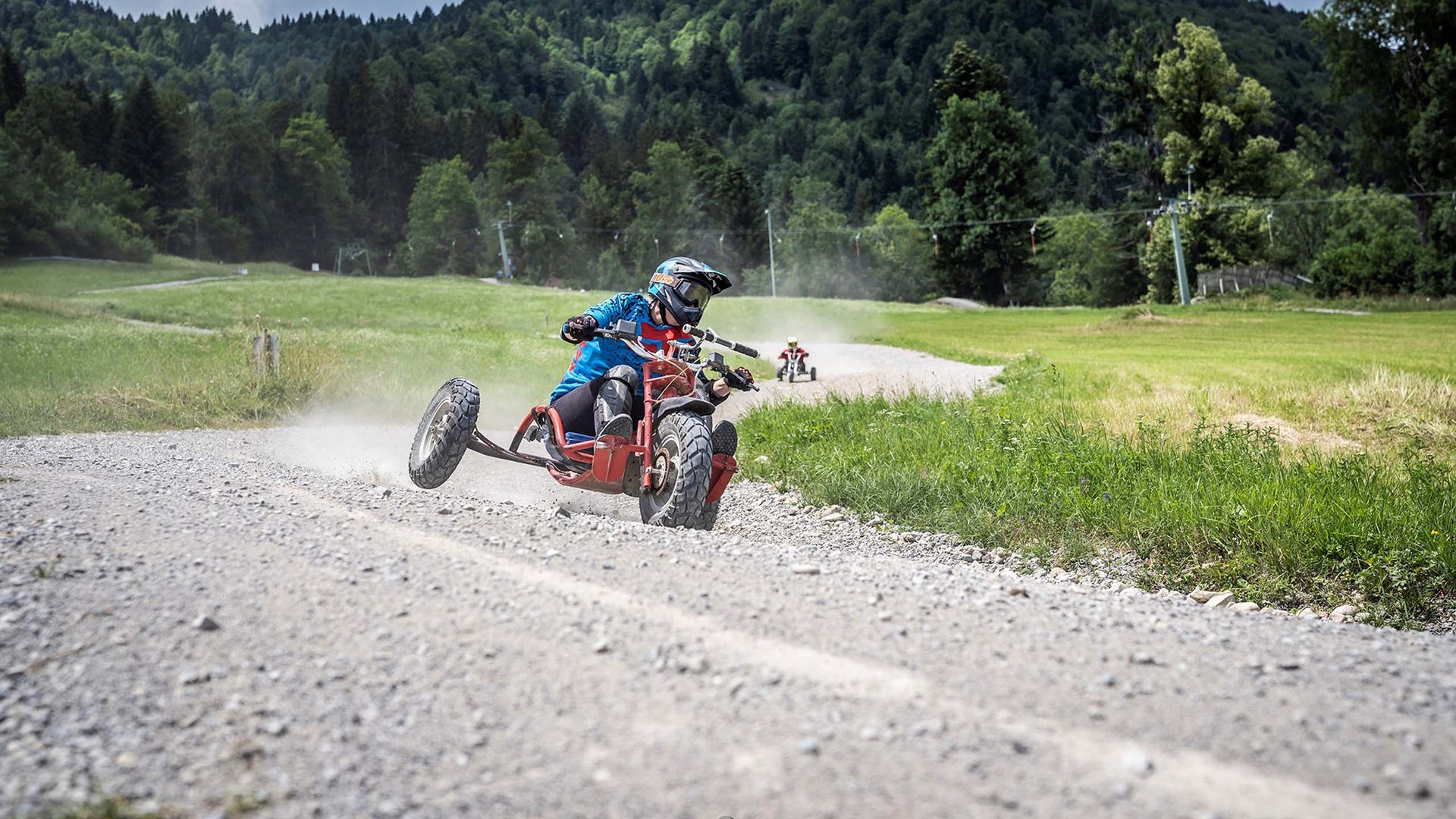 Urlaub in der Natur Bayerns Person fährt auf einem dreirädrigen Motorrad auf einem Schotterweg im Gebirge