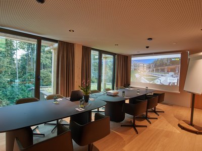 The adult-only hotel in Bavaria, Germany Modern conference room with tables, chairs, projector, and view of forest outside