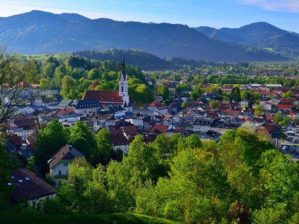 Sehenswert: Bad Tölz Blick auf eine Stadt mit Kirche und Bergen im Hintergrund an einem sonnigen Tag