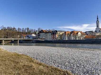 Sehenswert: Bad Tölz Blick auf die Altstadt von Weißbach mit Brücke, Fluss und Kirche bei blauem Himmel