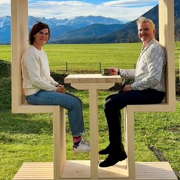 Holiday at BERGEBLICK in Bad Tölz Two people sitting on wooden frame seats with mountains in the background