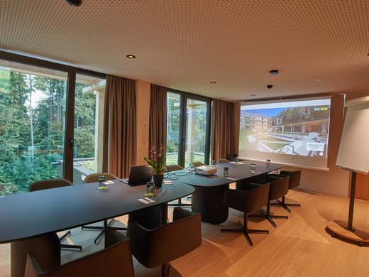 BERGEBLICK: dein Tagungshotel in Bayern Moderner Konferenzraum mit Tischen, Stühlen, Projektor und Blick auf Wald