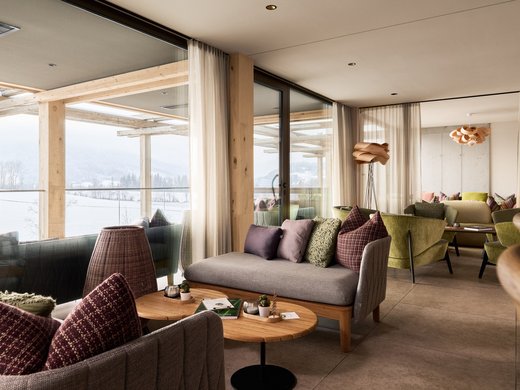 Hotel BERGEBLICK für Wellness in Bad Tölz Gemütlicher Lounge-Bereich mit Sofas und Panoramafenstern in modernem Design