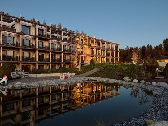 Holiday at BERGEBLICK in Bad Tölz Modern wooden building with pond and garden in evening light