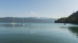Your active summer holiday in Bavaria Three sailboats on calm lake with forested hills and clear sky in background