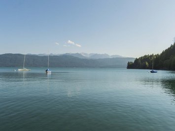 Urlaub im Aktivhotel in Bayern Drei Segelboote auf ruhigem See vor bewaldeten Bergen und klarem Himmel