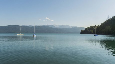 Pictures of a dream holiday in Bad Tölz Three sailboats on calm lake with forested hills and clear sky in background