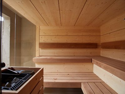 Hotel mit E-Bike-Verleih in Bayern: BERGEBLICK Innenansicht einer modernen Holzsauna mit Bänken und Saunaofen