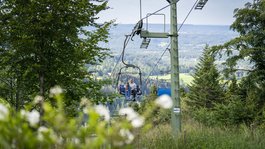 Urlaub in der Natur Bayerns Mutter und Kind auf Sessellift im grünen Wald mit Bergpanorama