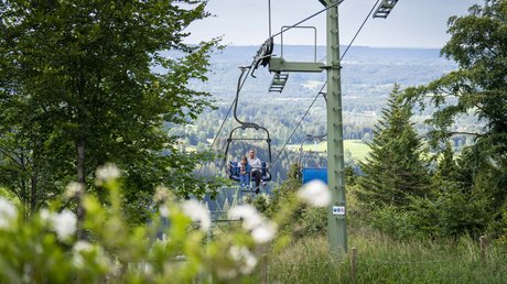 Pictures of a dream holiday in Bad Tölz Mother and child on chairlift in green forest with mountain view