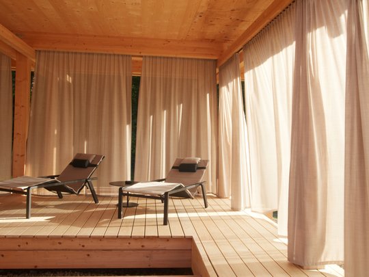 Holiday at BERGEBLICK in Bad Tölz Two lounge chairs on wooden deck with curtains in warm sunlight