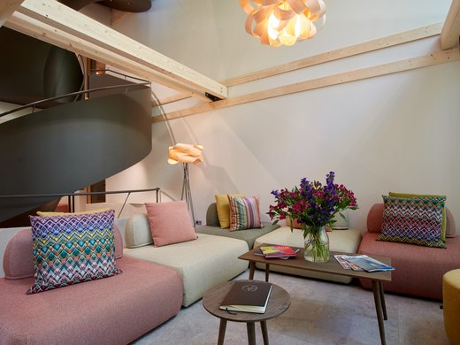 A holiday amidst nature in Germany Modern living room with colorful cushions, wooden ceiling beams, and flower vase on table