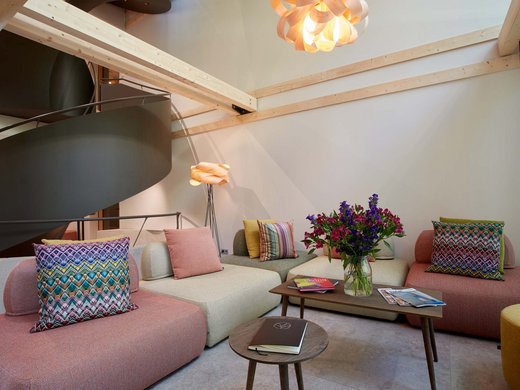 A holiday amidst nature in Germany Modern living room with colorful cushions, wooden ceiling beams, and flower vase on table