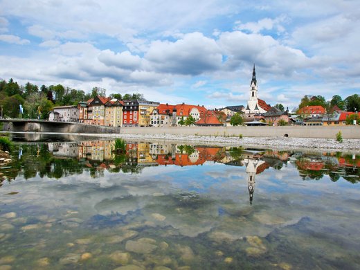 BERGEBLICK: dein Wanderhotel in Bayern Stadt mit Kirche und Häusern am Fluss mit Spiegelung im Wasser
