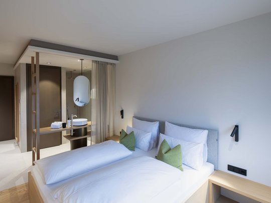 Wissenswertes aus Bad Tölz Modernes Hotelzimmer mit Doppelbett und offenem Waschbereich