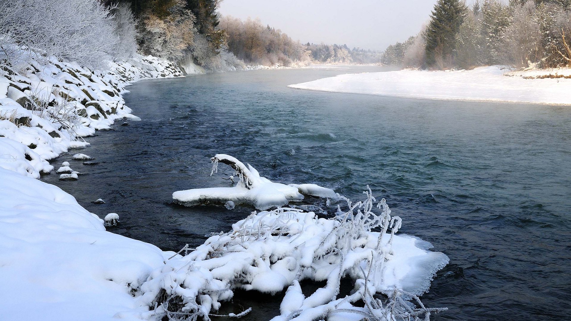 Your active summer holiday in Bavaria Snow-covered river with frost-covered branches and trees in winter