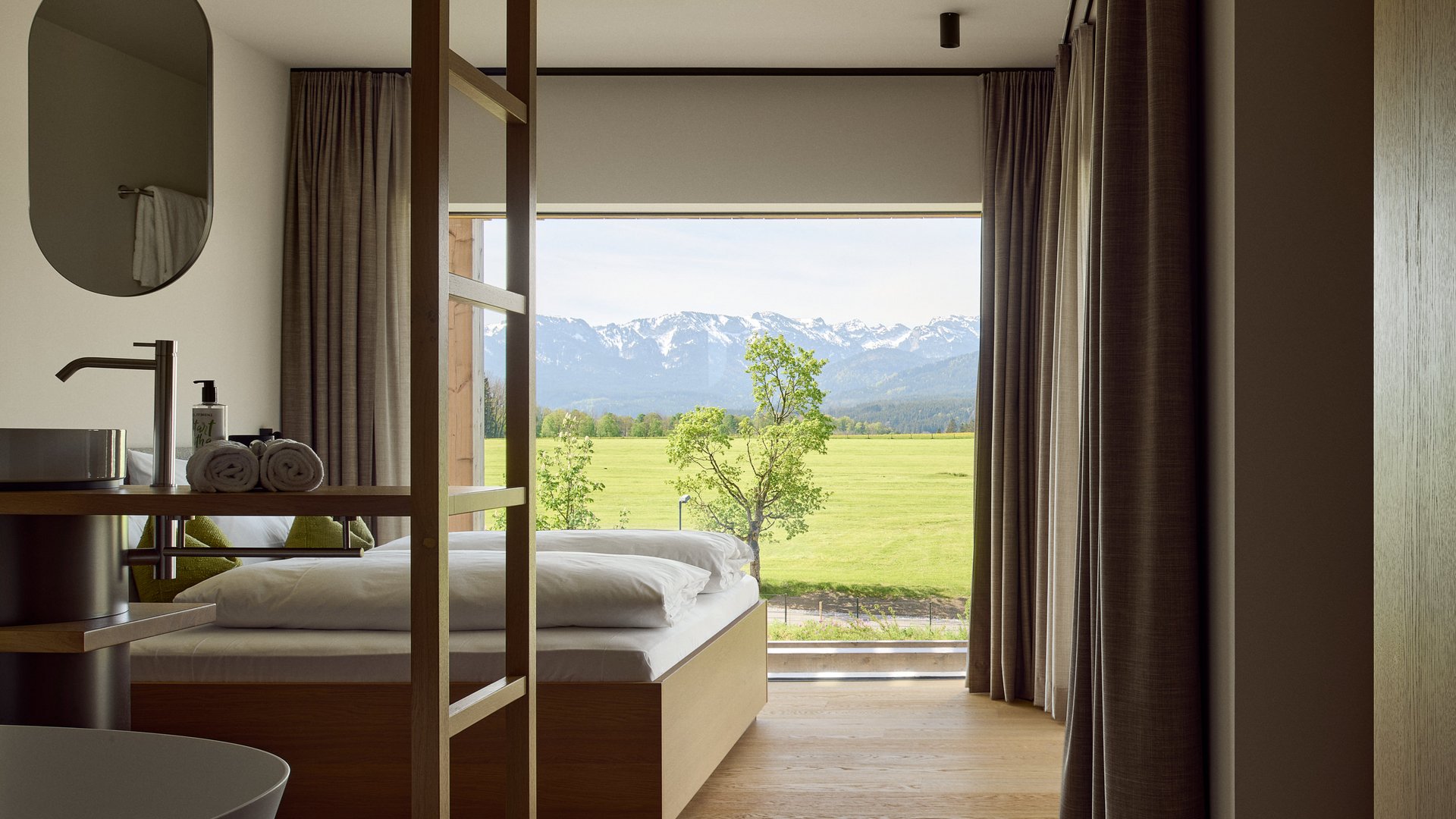 Holiday at BERGEBLICK in Bad Tölz Modern hotel room with large window overlooking green field and mountains