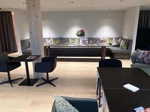 Deine Lounge für Business & Genuss Moderne Lounge mit Sitzbank, Tischen, Stühlen und Blumen auf dem Tisch