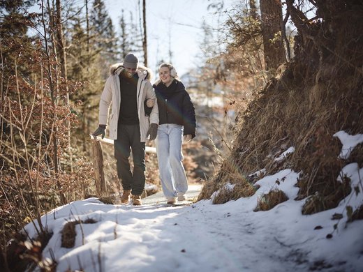 Your active holiday in Bavaria in Bad Tölz Couple walking on a snowy forest path in winter