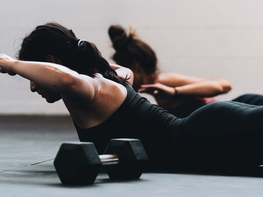 Your yoga hotel in Bavaria: BERGEBLICK Two women doing back exercises on the floor with dumbbells in a gym
