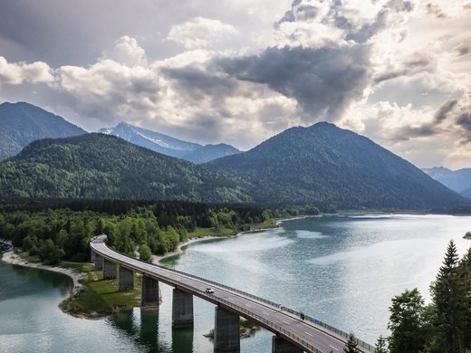 Traumhafter Sylvensteinsee Brücke über einen See mit Bergen und bewölktem Himmel im Hintergrund