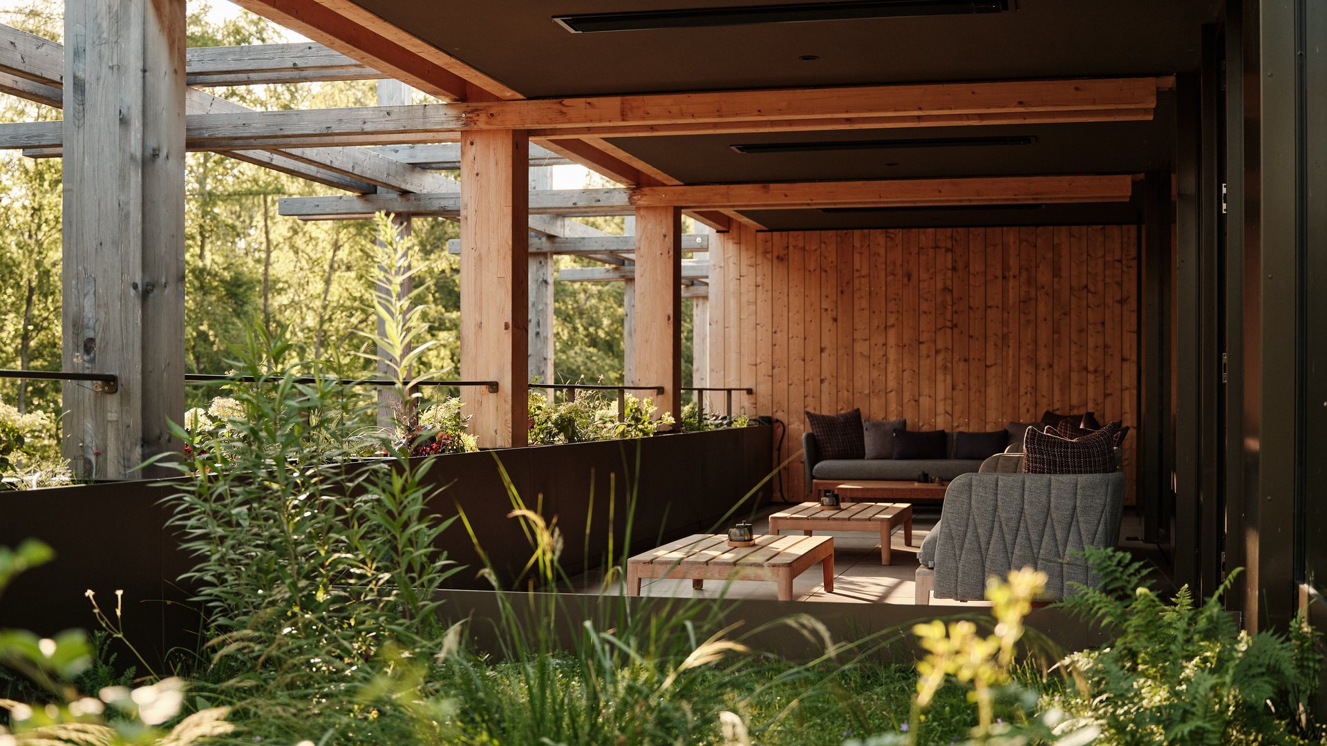 Dein Wellnesshotel in Bad Tölz: BERGEBLICK Gemütliche überdachte Terrasse mit Holzverkleidung und Sitzmöbeln umgeben von Pflanzen