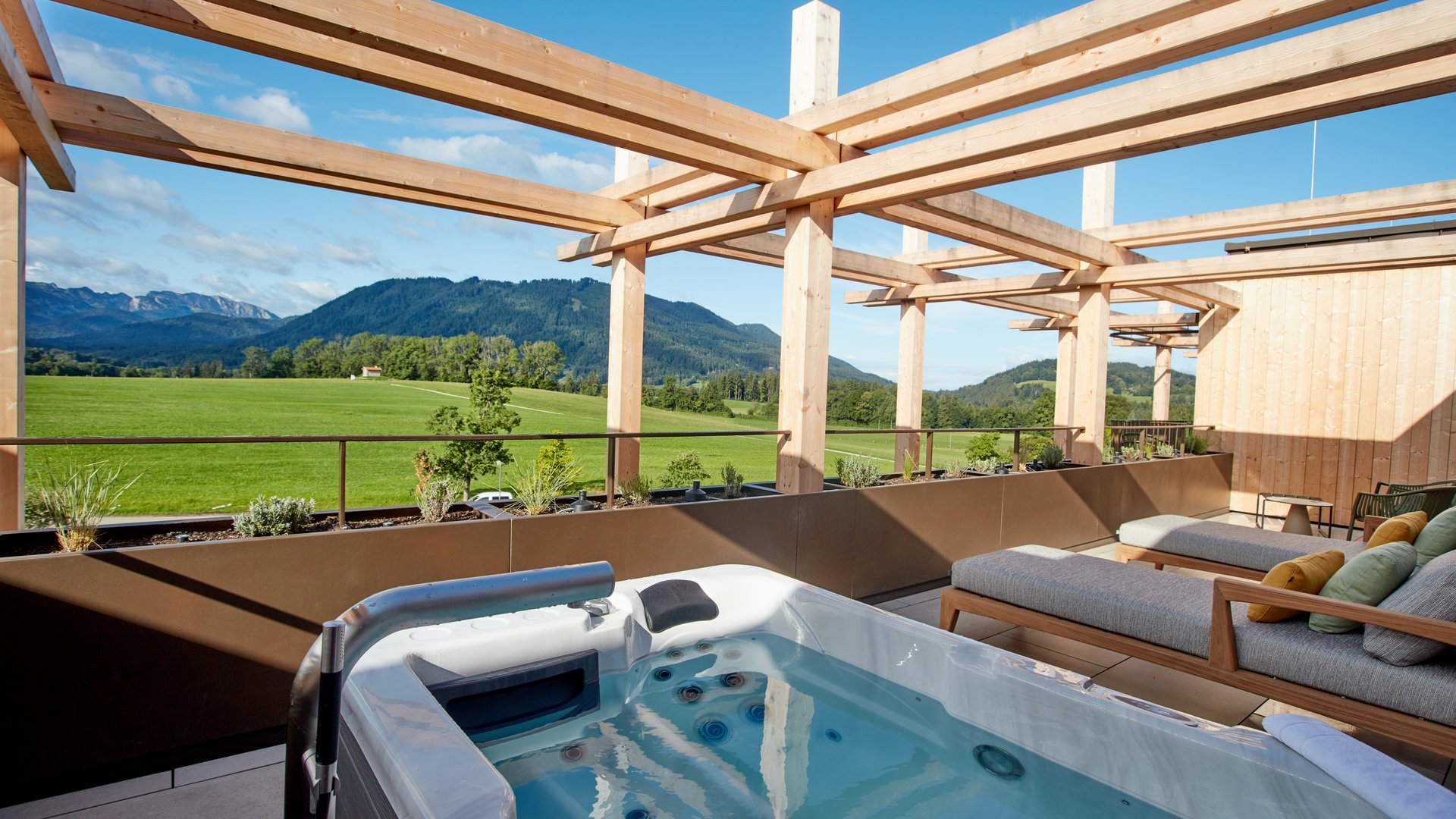 Gartensuite in Bayern mit BERGEBLICK Terrasse mit Whirlpool und Liegestühlen mit Blick auf grüne Wiesen und Berge