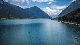 Your active summer holiday in Bavaria Two kayakers on a lake surrounded by mountains under a cloudy sky