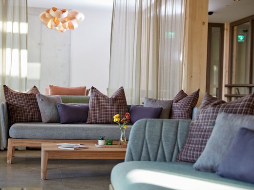 A holiday amidst nature in Germany Modern living room with gray sofas, patterned cushions, and wooden table with flowers