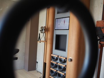 Dein Sporthotel in Bayern – Aktivurlaub im BERGEBLICK Blick durch einen Trainingsring auf ein Multifunktions-Trainingsgerät mit Bildschirm