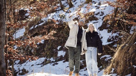 Pictures of a dream holiday in Bad Tölz Couple hiking in snowy forest, man pointing ahead