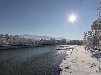 Sehenswert: Bad Tölz Winterliche Flusslandschaft mit Schnee bedeckten Bäumen und klarem Himmel