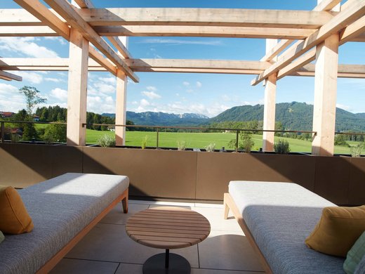 Your holiday in nature in Bavaria: Hotel BERGEBLICK Two modern loungers on a terrace overlooking green fields and mountains