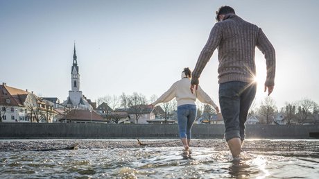 Pictures of a dream holiday in Bad Tölz Couple wading barefoot in a river near a village with church tower at sunset