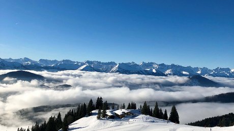 Pictures of a dream holiday in Bad Tölz Snow-covered mountains with houses, trees, and clouds under a blue sky