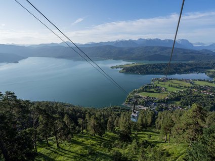 Sehenswert: Bad Tölz Seilbahn über bewaldeten Hügel mit Blick auf See und Berge im Hintergrund