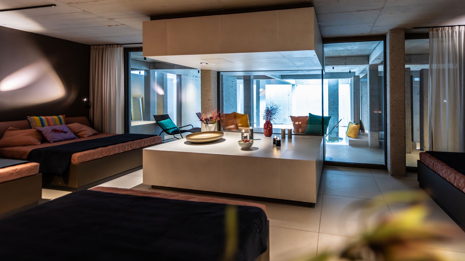 Modern living room with sofas, glass walls, and a decorative centerpiece with candles