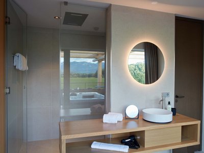 Your romantic hotel in Germany with mountain views Modern bathroom with illuminated round mirror and mountain view